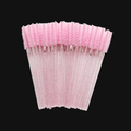 Pink and clear decorative lash wands or lash spoolies on a black background