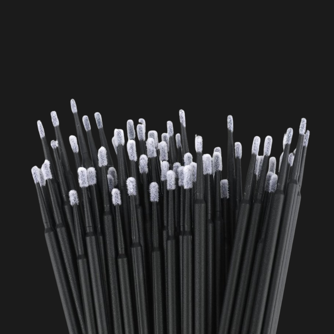 Collection of black eyelash extensions micro brushes laying on a black background